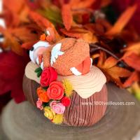 Handcrafted figurine of a baby in polymer clay dressed as a fox on a wooden log