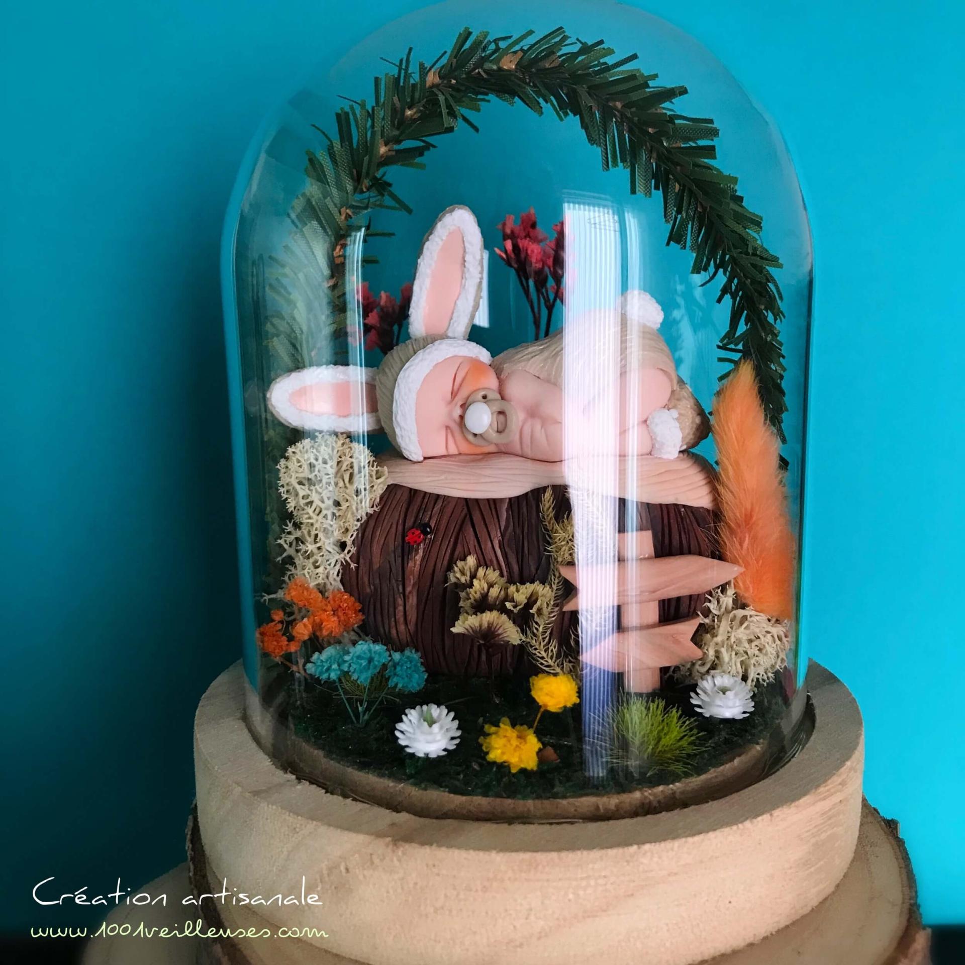 Personalized and handmade glass and wood night light presented turned off with a baby dressed as a rabbit under a glass dome