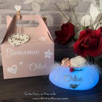 Multicolored LED personalized pebble with baby sculpted in fimo dressed as an angel next to its rose, with customizable gift box, overall view of the illuminated night light